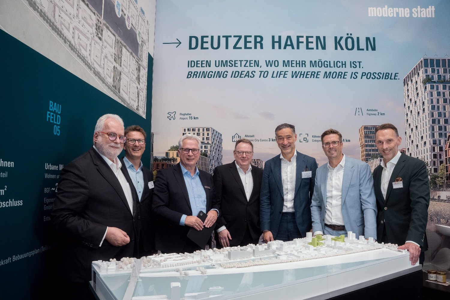 Sieben Personen am Stand von moderne stadt auf der Expo Real 2026, vor ihnen das Modell des Deutzer Hafens