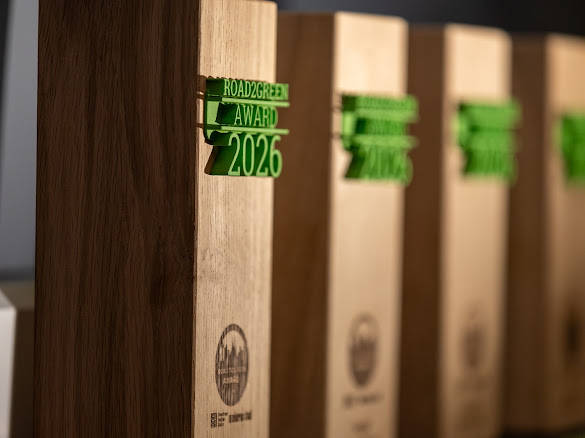 Hölzerne Auszeichnungen mit grüner Gravur „ROAD2GREEN AWARD 2026" in einer Reihe
